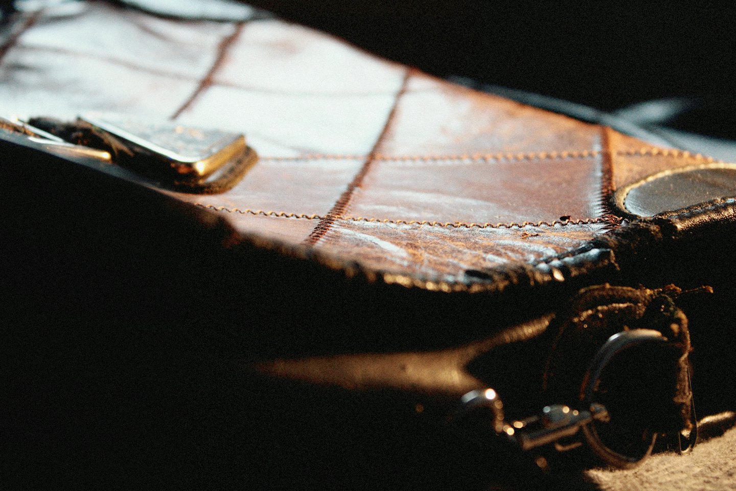 Close-up van een bruine leren tas met gedetailleerd stikwerk.